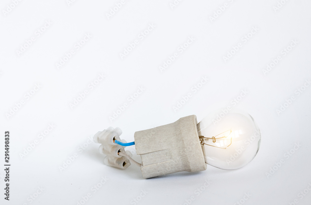 Lighting incandescent lamp bulb with cap, socket, wires and terminal block lies on white background, new idea concept Lighting incandescent lamp bulb with cap, socket, wires and terminal block lies on white background, new idea concept