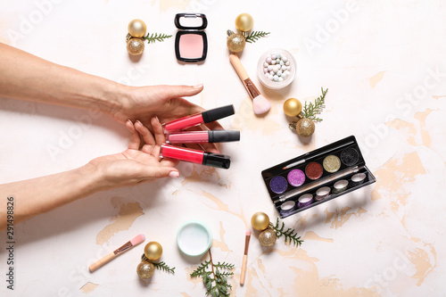 Female hands with cosmetics and Christmas decor on white background