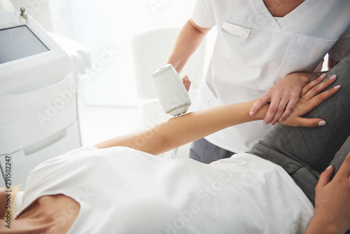Young lady in white t-shirt receiving laser epilation in beauty salon