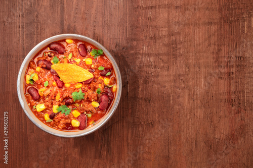 Chili con carne, shot from above on a dark rustic wooden background with a place for text