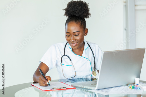 Doctor working in hospital writing a prescription, Healthcare and medical concept,test results in background, Stethoscope with clipboard and Laptop on desk