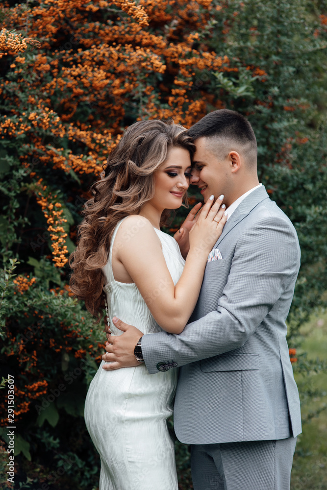 Beautiful wedding photos in summer. Beautiful young couple hugging among the branches of sea buckthorn. Beautiful couple are walking in the park at summer. Beautiful young couple tenderly kissing Beautiful wedding photos in summer. Beautiful young couple hugging among the branches of sea buckthorn. Beautiful couple are walking in the park at summer. Beautiful young couple tenderly kissing