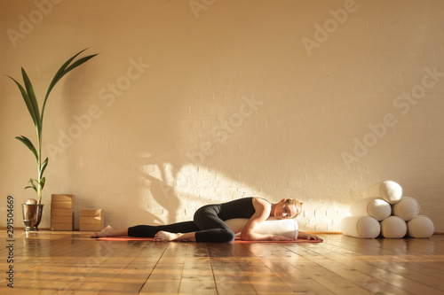 Print op canvas Woman practiving restorative yoga in a beautiful studio