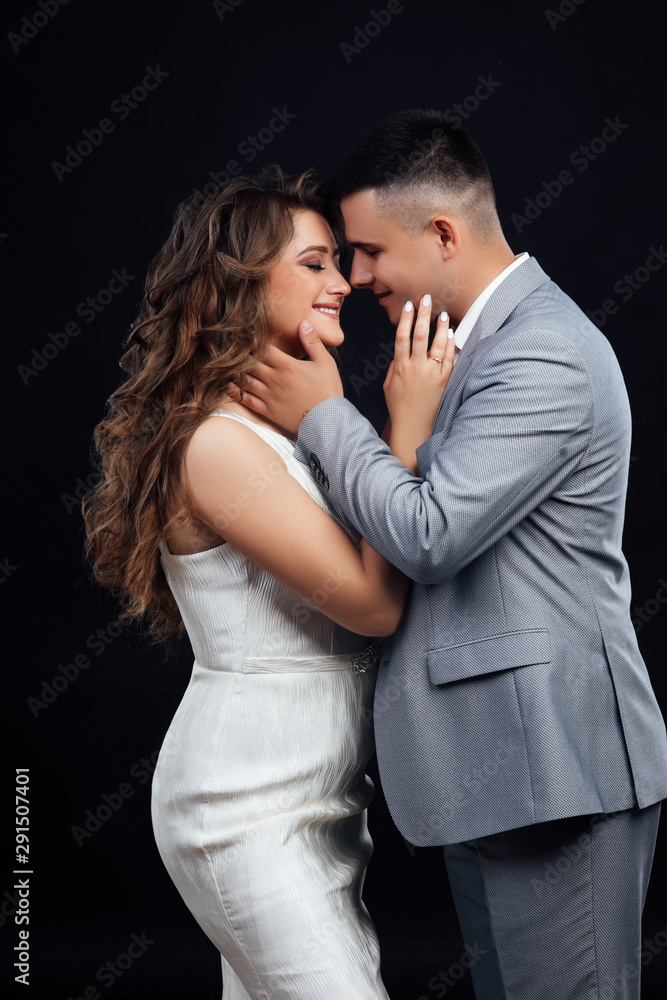 Close up on a romantic couple - black background. Young beautiful woman and her boyfriend in love in a studio. Happy lovers being together and showing affection. Young attractive couple