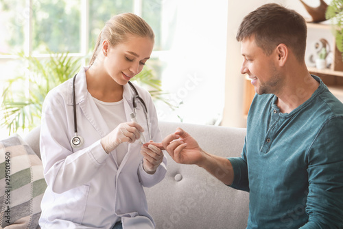 Doctor taking blood sample of diabetic man at home