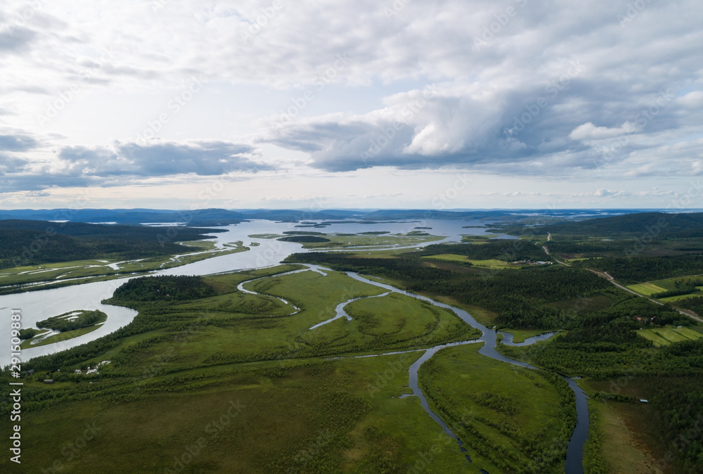 Aerial view of blue river, lake and green forests on a summer day in Lapland. Drone photography. Ivalojoki.