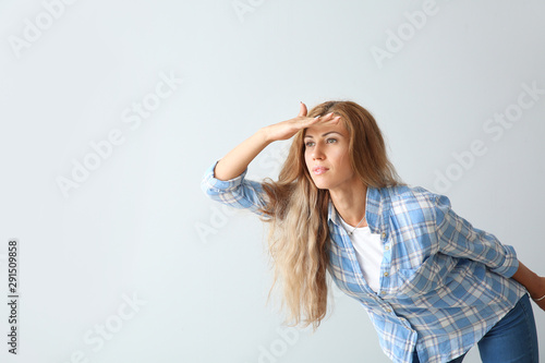 Beautiful young woman looking faraway on light background