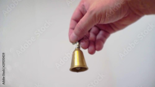 hand shakes a small yellow metal bell.close-up.shallow depth of field.