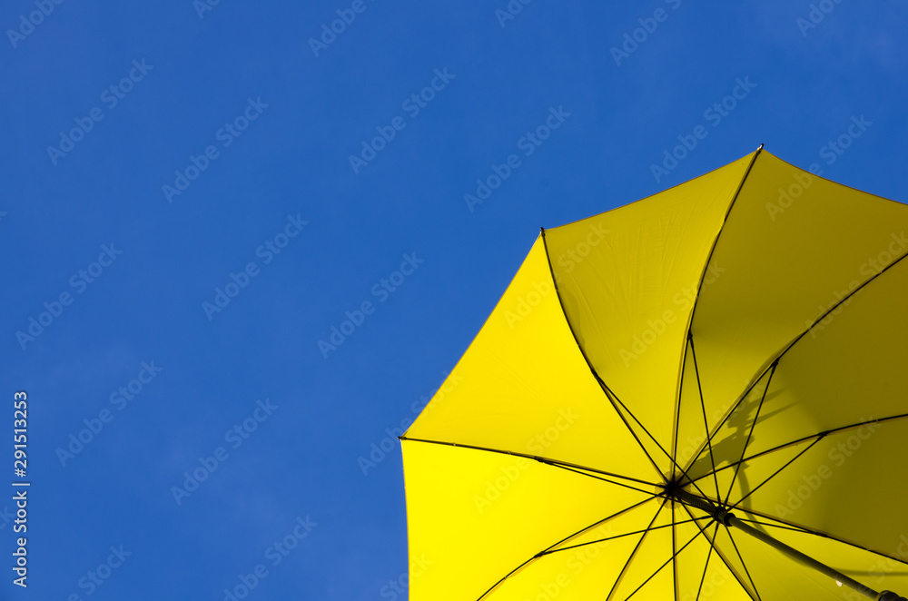 Yellow parasol against a sunny clear blue sky