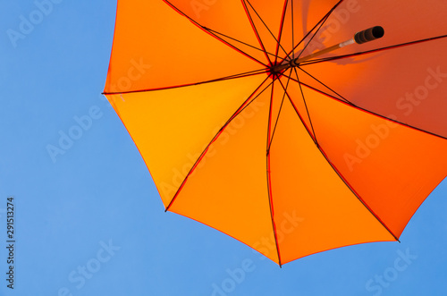 Orange parasol against a sunny clear blue sky