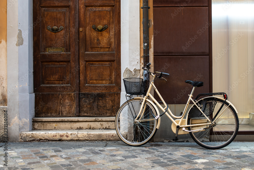 Beige bike with basket on italian street. Typical italian architecture on background.