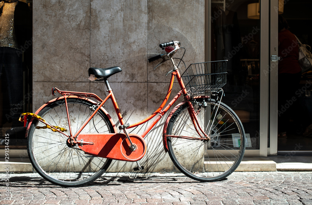 Red bike with basket on italian street. Typical italian architecture on background.