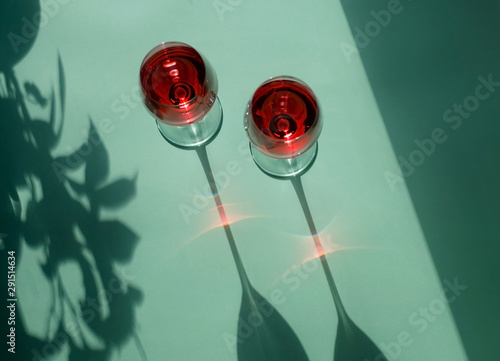 Two glasses of red wine on a light green background. Beautiful still life with wine on a Sunny day.