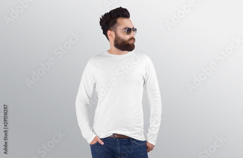 Closeup of standing male model wearing white plain crew neck long sleeve shirt in blue denim jeans pant. Isolated background