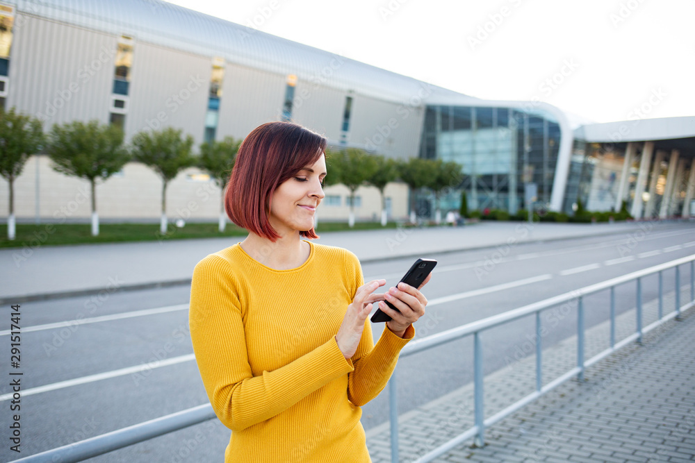 Fototapeta premium Beautiful girl uses a smartphone. View photos and videos on the phone.