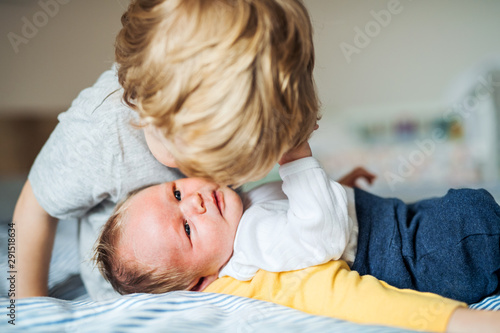 A small boy kissing a newborn baby brother at home.