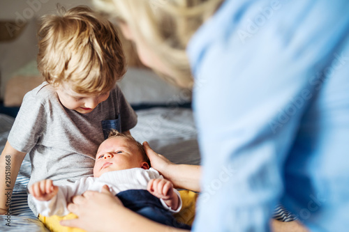 Photography A young mother with a newborn baby and his brother at home.