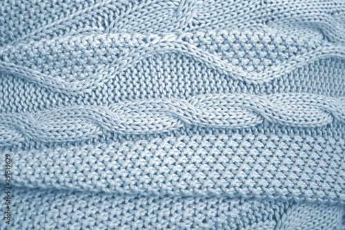 Blue knitted blanket or plaid with a braid pattern. The knitted fabric, soft and warm, wrinkled. Texture for background.