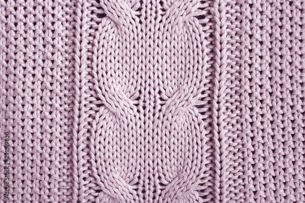 Rose knitted plaid with braid pattern. Close-up photo top view. Home background.