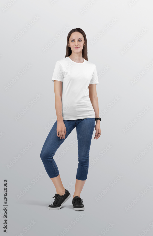 Standing beautiful female model wearing white plain crew neck t shirt in blue denim jeans capri pant. Isolated background Standing beautiful female model wearing white plain crew neck t shirt in blue denim jeans capri pant. Isolated background