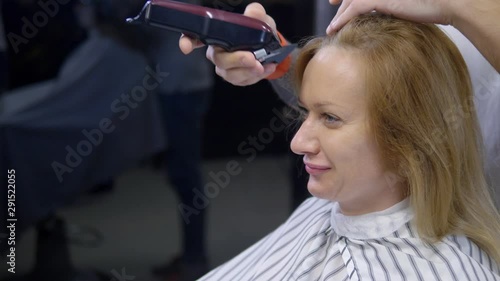 Woman shaving her head baldly. a hairdresser shaves a woman's long hair with a hair clipper. photo