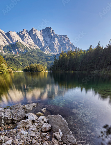 Portrait panorama of the crystal clear water of the Eibsee with the Zugspitze mountain including reflection in the background