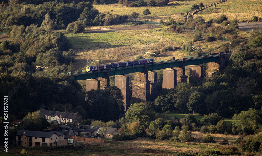 A train travelling over an old bridge in the centre of Glossop