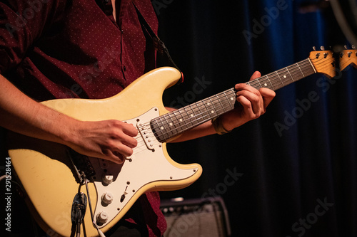 Male guitarist playing an electric stratocaster guitar on a gig