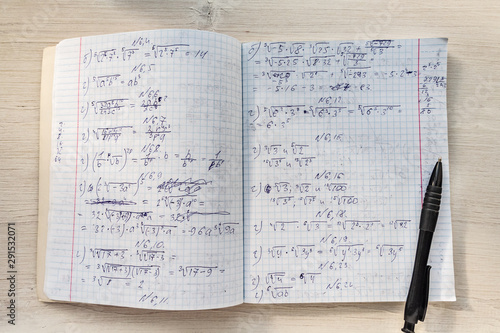 School notebook in a cage and pen with a mathematical calculation. High school notebook on the table.