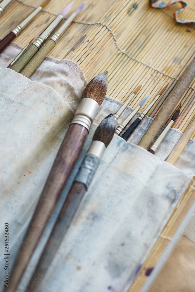 Artist paint brushes and watercolor paintbox on plastic palette.