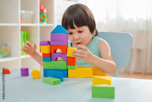 little girl collects a wooden unpainted pyramid. Safe natural wooden children's toys.