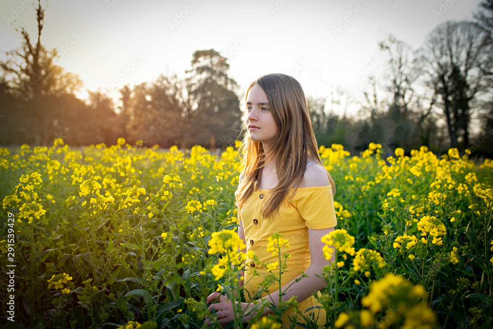 Young girl walking through yellow and green spring countryside fields Young girl walking through yellow and green spring countryside fields