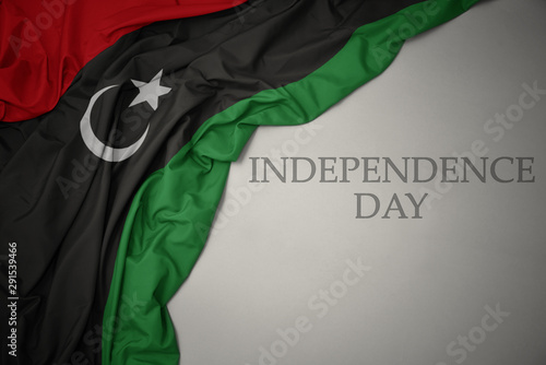 Bilde på lerret waving colorful national flag of libya on a gray background with text independence day