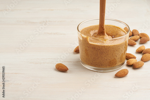 almond butter, raw food paste made from grinding almonds into nut butter, crunchy and stir, white wooden table, copy space