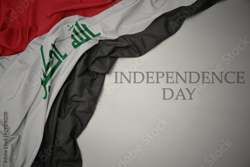waving colorful national flag of iraq on a gray background with text independence day.