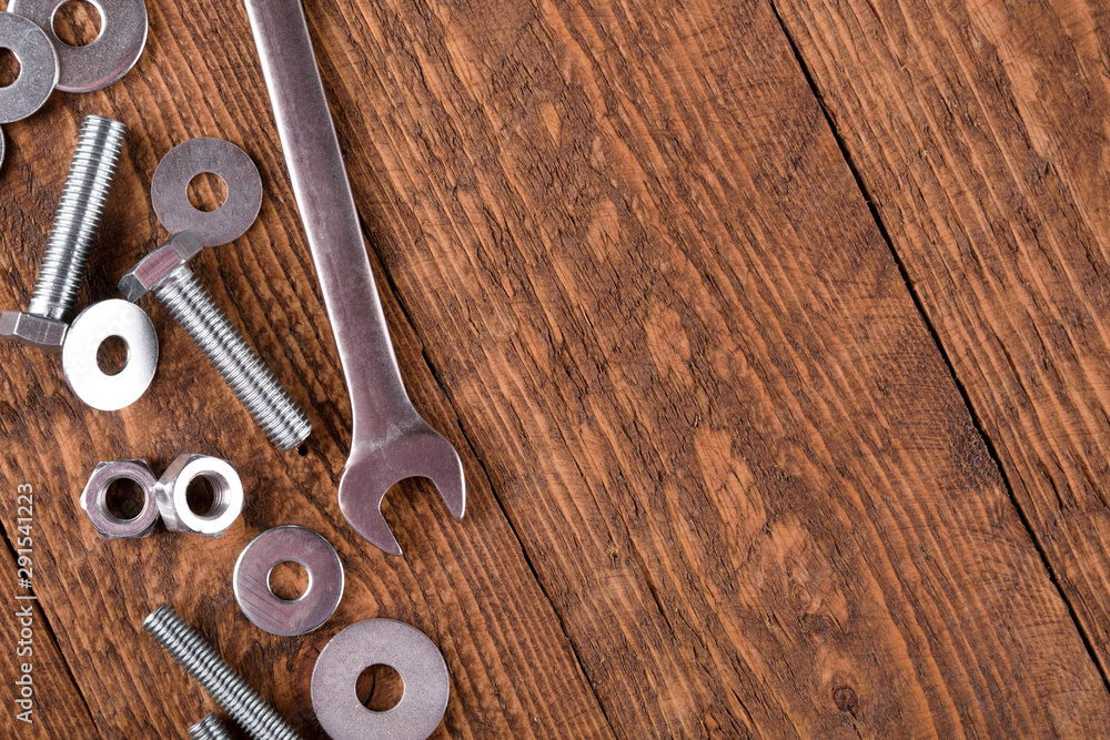 Keys wrenches, bolts, nuts, washers on a wooden background Keys wrenches, bolts, nuts, washers on a wooden background