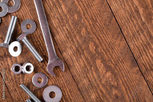 Keys wrenches, bolts, nuts, washers on a wooden background