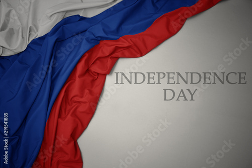 waving colorful national flag of russia on a gray background with text independence day.