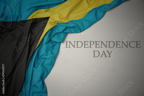waving colorful national flag of bahamas on a gray background with text independence day.