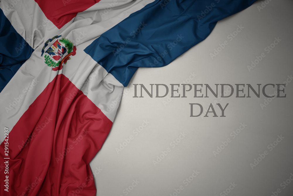 waving colorful national flag of dominican republic on a gray background with text independence day. - obrazy, fototapety, plakaty 
