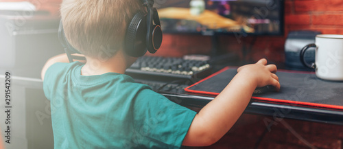 little boy playing games on computer in headphones with microphone, computer game