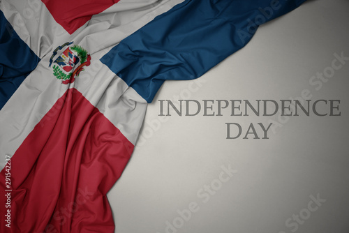 waving colorful national flag of dominican republic on a gray background with text independence day. photo