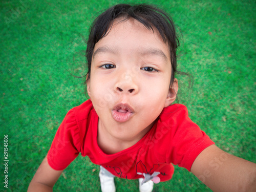Asia kid girl smiling playing in the field, Happy and Stick out tongue, looking to camera.