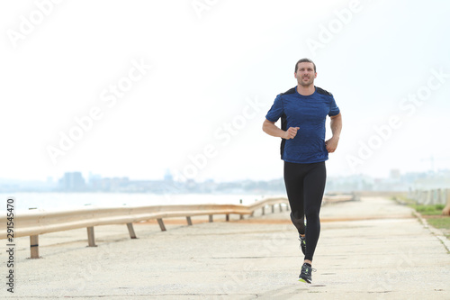 Front view of runner running on the beach