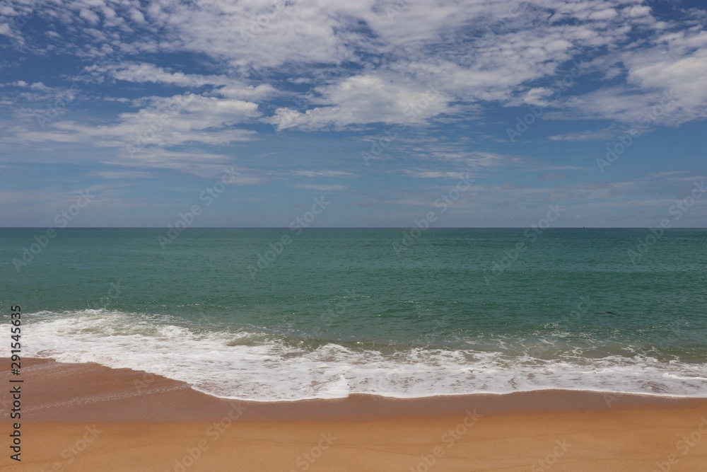 Picturesque seascape with azure water, blue sky and white clouds. View of the foaming ocean wave lapping at the sandy shore Picturesque seascape with azure water, blue sky and white clouds. View of the foaming ocean wave lapping at the sandy shore