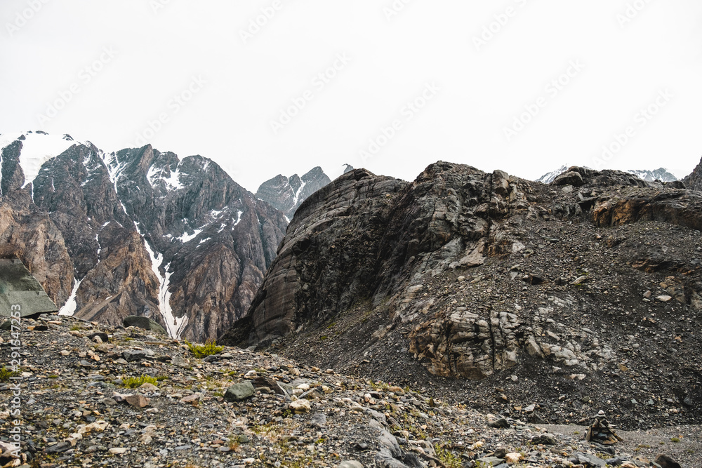 The slopes of high snowy mountain ranges. An embankment of many small stones. Beautiful views of difficult to climb, sharp mountains in a tourist trip through the nature of Altai land. 
