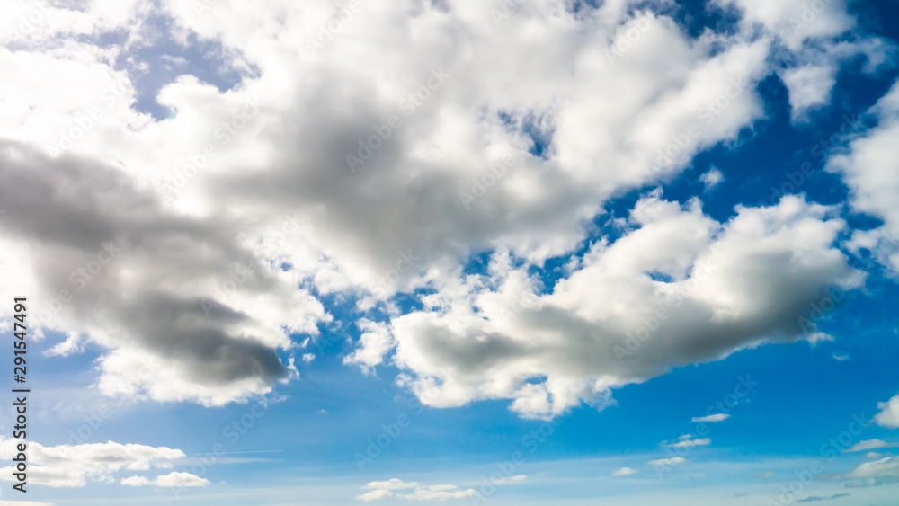 Fototapeta premium Vibrant blue sky background with white fluffy clouds taken on a warm spring/summer day.