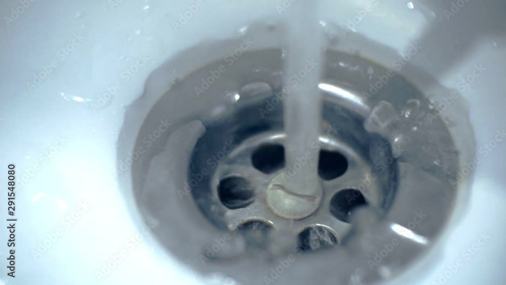 water pours into the hole in the sink in the bathroom.close-up.shallow depth of field. water pours into the hole in the sink in the bathroom.close-up.shallow depth of field.