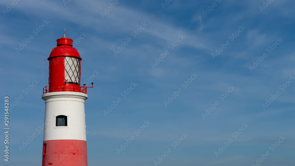 Souter Lighthouse, at Marsden Bay, South Shields, Tyne and Wear, England UK. With blue sky background and clouds. Image shows red top of lighthouse with light lenses. Souter Lighthouse, at Marsden Bay, South Shields, Tyne and Wear, England UK. With blue sky background and clouds. Image shows red top of lighthouse with light lenses.