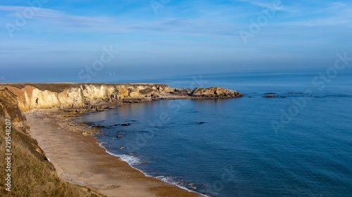 Marsden Bay in South Shields, England UK. View from the Leas cliff tops showing Marsden Bay's rocky coastline on the left and the North Sea on the right. Blue sea and a beautiful summer sky.
